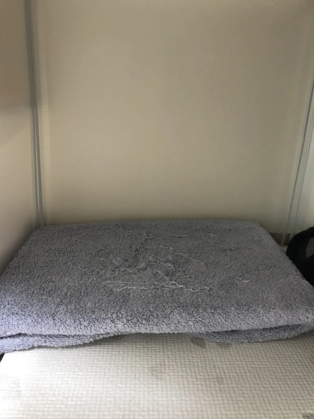Completed cooling setup inside a rabbit cage — towel-wrapped cooling mat with edges tucked under