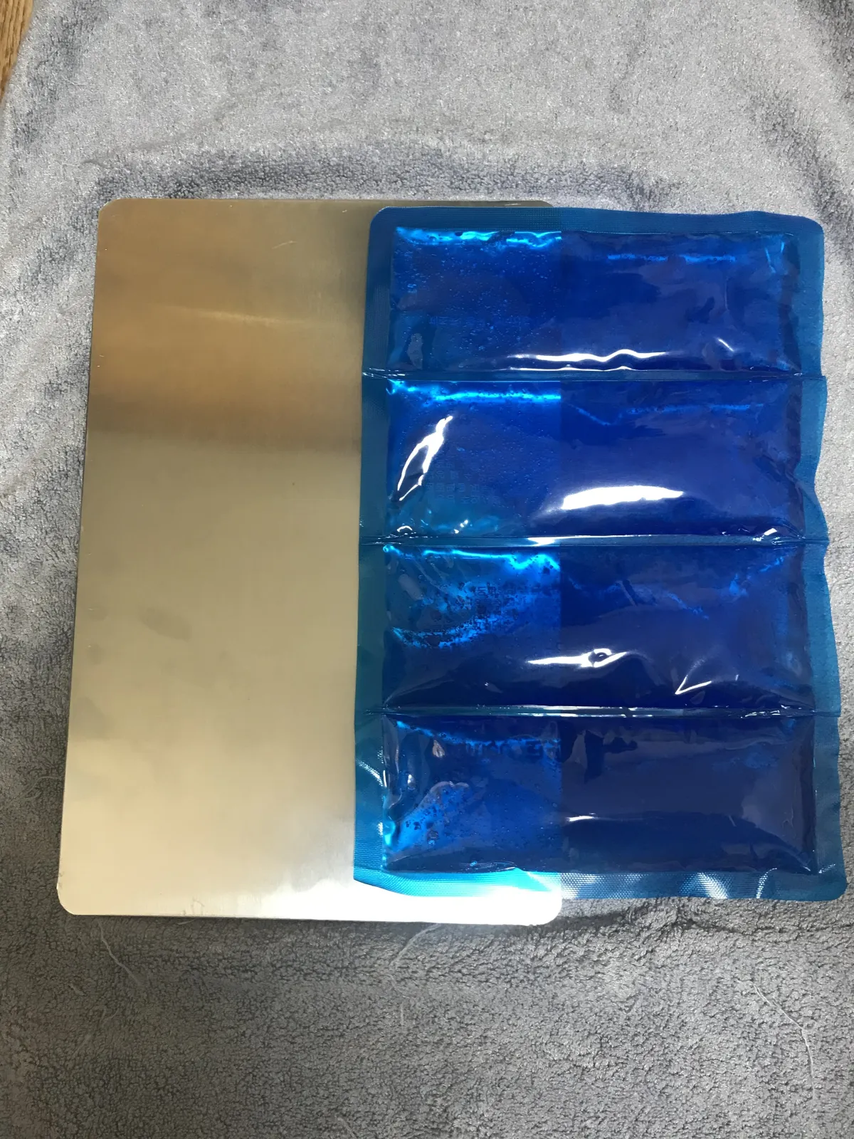 Blue gel ice pack next to a stainless steel cooling mat — the two main components of my rabbit cooling setup