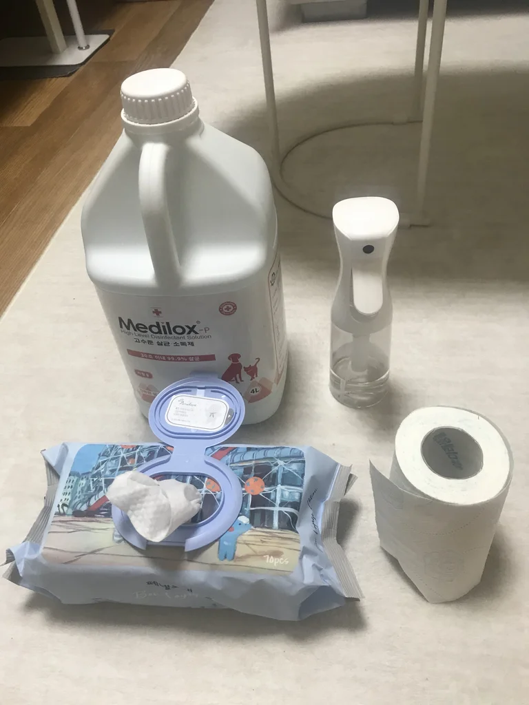 Rabbit cage cleaning supplies: Medilox hypochlorous acid disinfectant, spray bottle, pet wet wipes and a paper towel roll
