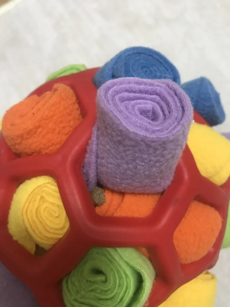 Close-up of a snuffle ball with a timothy pellet tucked between rolled fleece strips